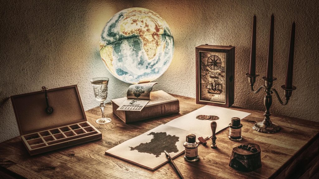 a table with a desk globe, a map, candles and a fountain pen on top
