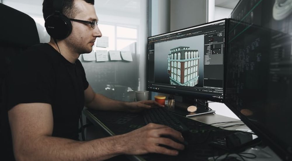 3D artist working with Blender (software) on his computer.