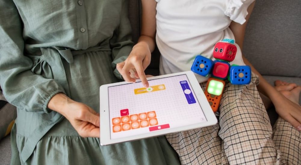 A child playing an educational game on the tablet with his mother.