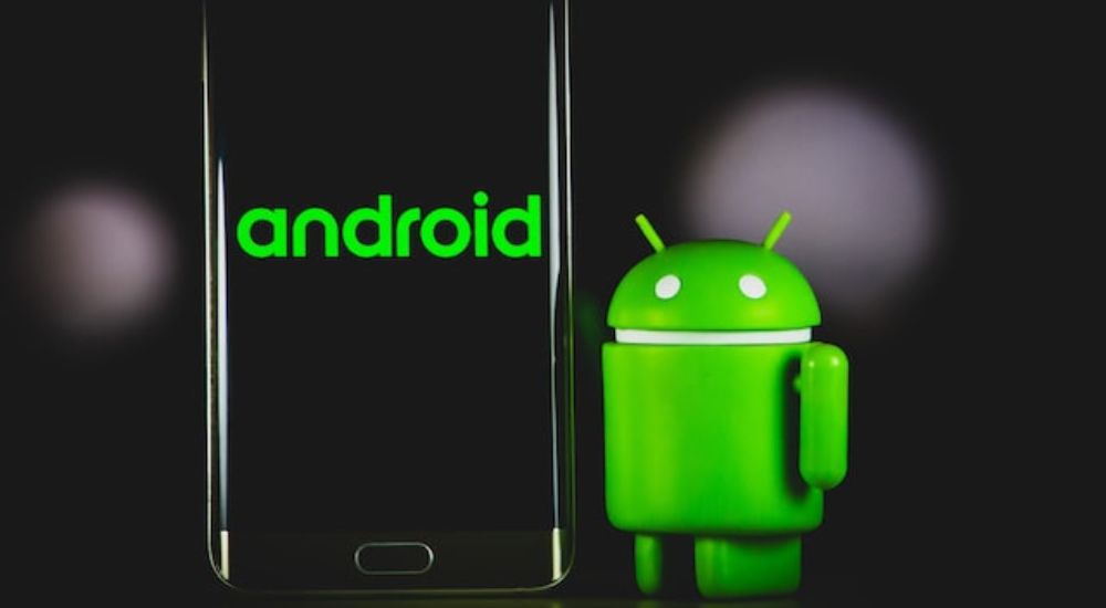 A phone beside the Android logo on a black background