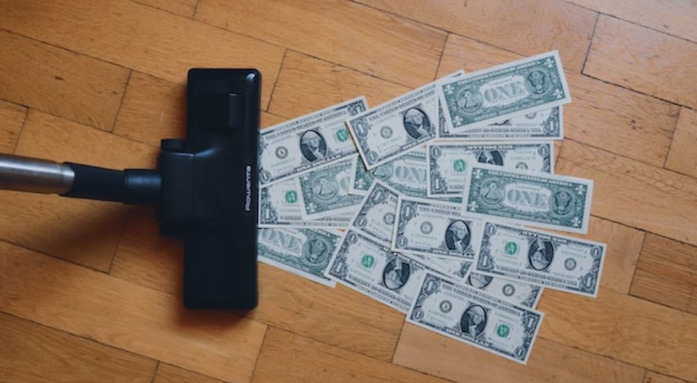 A vacuum cleaner sucking up some dollar bills.