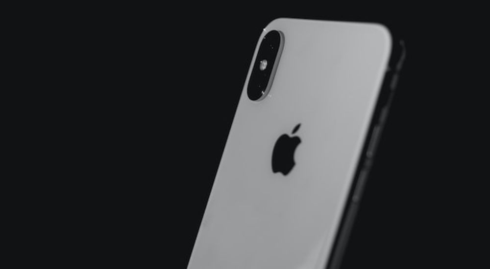 A white Iphone on a black background.