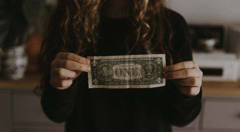 A woman holding a dollar bill.