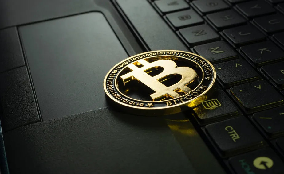 Uma moeda Bitcoin sobre um teclado de notebook.