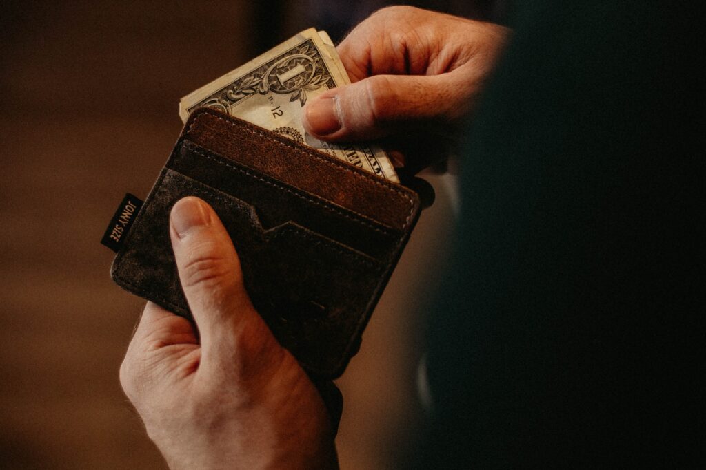 A man taking out a $1 bill from his wallet.