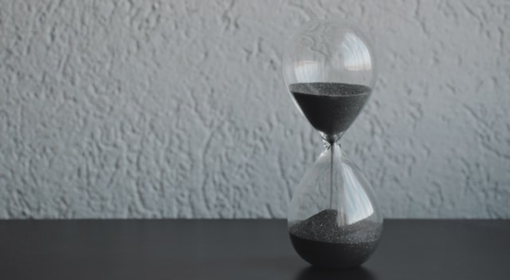 Photograph of an hourglass with gray sand.