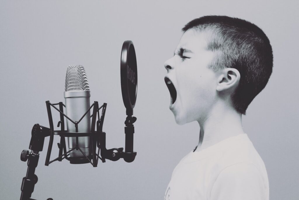 A black and white picture of a kid screaming into a microphone.