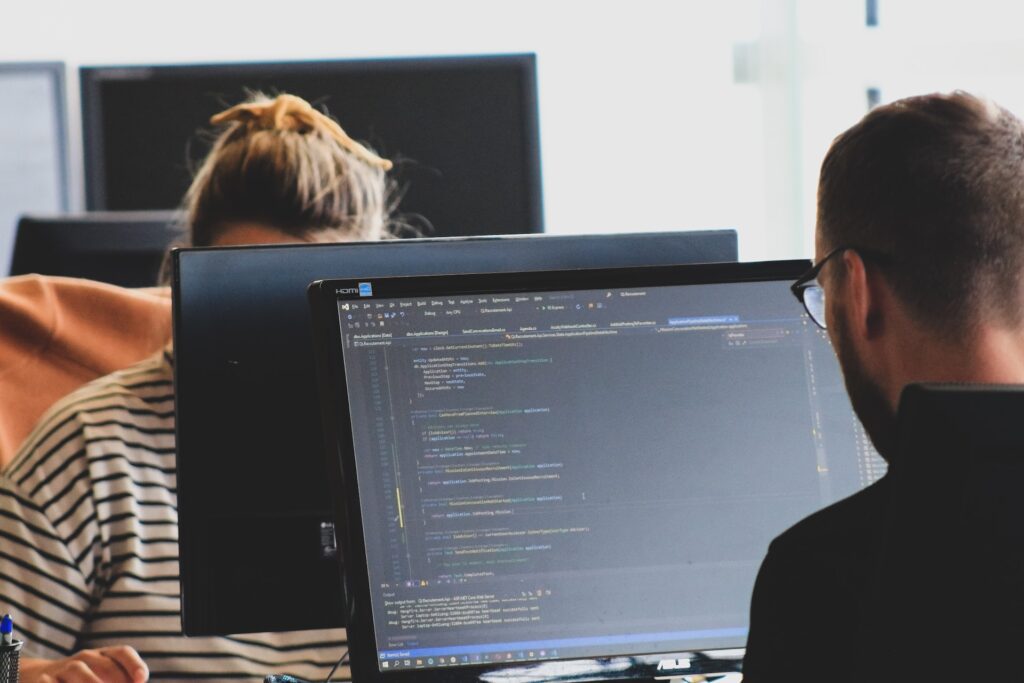 Two people working in an office environment on their computers.