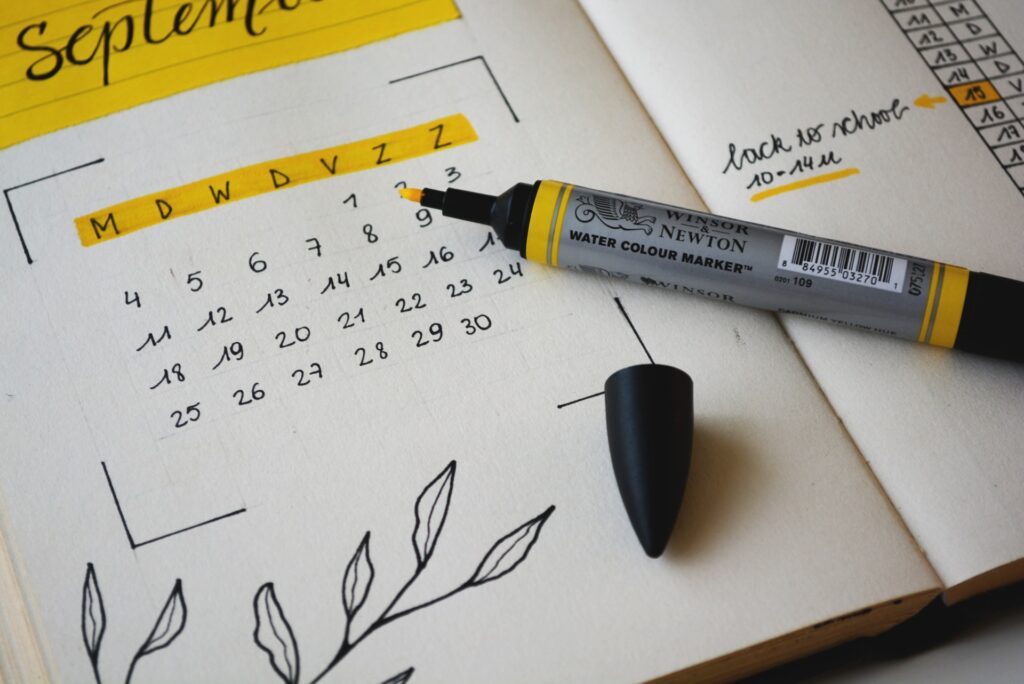 A photograph of a hand-drawn calendar. A yellow market sits on top of it.